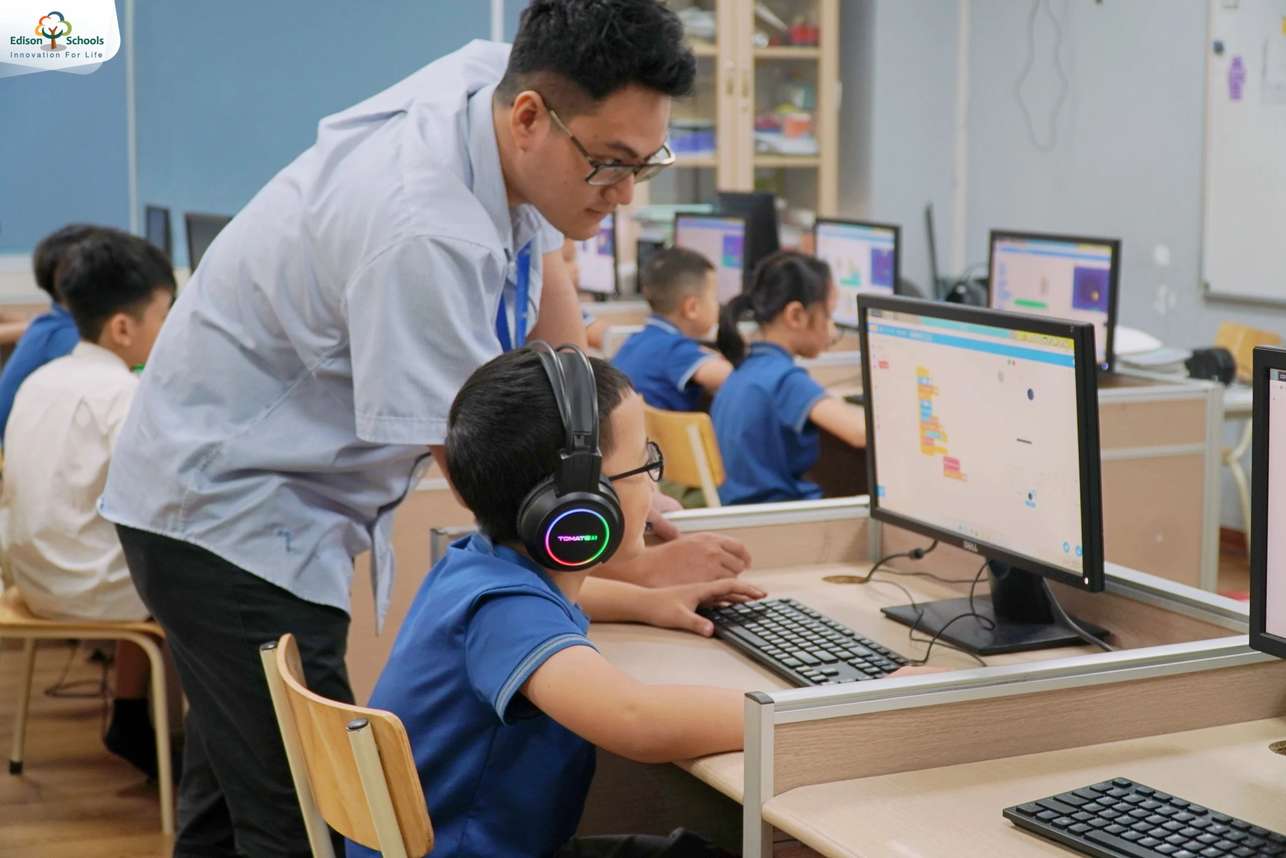 Giáo viên Edison hướng dẫn học sinh tiểu học học AI trên máy tính trong lớp học công nghệ